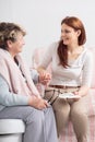 Caregiver talking with smiling senior woman while visit her at nursing house