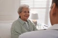 Caregiver talking to senior woman in living room. Home health care service Royalty Free Stock Photo