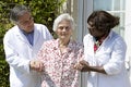 Caregivers assisting a senior patient walking outside