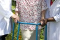 Caregivers helping a senior patient with her walker outdoor