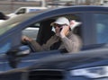 Careless male driver with sunglasses and cap using mobile phone while driving in heavy traffic. Careless or reckless driving is a