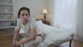 Careless young man sitting in bedroom as angry woman hitting with pillow crying leaving. Portrait of negligent Caucasian