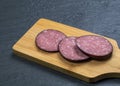 Carelessly chopped slices of smoked sausage on a wooden cutting board Royalty Free Stock Photo