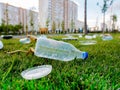 Carelessly discarded plastic bottles and food containers. Plastic garbage on the lawn in the courtyard of multi-storey