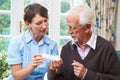 Carer Helping Senior Man With Medication