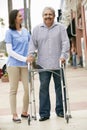 Carer Helping Senior Man To Use Walking Frame Royalty Free Stock Photo