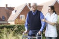 Carer Helping Senior Man To Walk In Garden Using Walking Frame Royalty Free Stock Photo