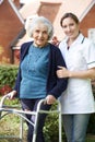 Carer Helping Senior Woman To Walk In Garden Using Walking Frame Royalty Free Stock Photo