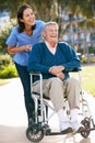 Carer Pushing Senior Man In Wheelchair