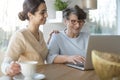 Caretaker and senior with laptop