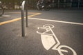 A cargo bike symbol painted on asphalt to mark a dedicated parking slot in a big city is passed by two female bicycle riders