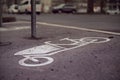 A cargo bike symbol is painted on the tarmac of a bicycle parking space in front of an urban grocery store.