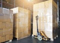 Cargo boxes shipment, Manufacturing and warehousing. Stack of cardboard boxes on pallet and hand pallet truck at warehouse storage Royalty Free Stock Photo