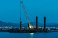 Cargo crane working in small port, construction of industrial harbor or dock in evening, sea goods transportation and Royalty Free Stock Photo