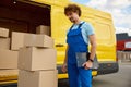 Cargo delivery service providing by professional courier standing by boxes stack