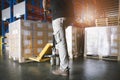 Cargo export, Shipment. Warehouse worker using hand pallet truck unloading a large pallet goods in the warehouse. Royalty Free Stock Photo