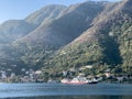 Cargo ferry sails along the sea along the coast of a small town at the foot of high mountains