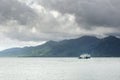 Cargo ferry in tropical sea under monsoon storm heavy clouds and tropical Koh Chang island on horizon in Thailand Royalty Free Stock Photo