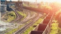 Cargo freight train wagons in sunlight go on railroad in industrial zone with plants and manufacturing factories of heavy industry Royalty Free Stock Photo