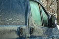 cargo minibus with handles and a window covered with a layer of dried dirt and dust.