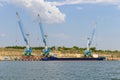 Cargo port cranes load a sea barge on a sunny day