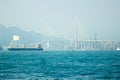 Cargo ship and boats floating in blue sea on car highway background. Tanker ship in blue ocean on car bridge landscape. Royalty Free Stock Photo