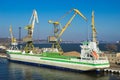 Cargo ship docked at international port, cranes loading containers under clear sky. Maritime freight transport, global Royalty Free Stock Photo