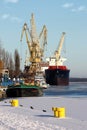 Cargo ship on harbor. Port crane and mooring bollards on a pier by frozen Odra River in Szczecin, Poland