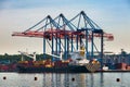 A cargo ship moored for loading at container yard with large cranes. Royalty Free Stock Photo