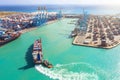 Cargo ship with multiple containers sails into the harbor seaport with industrial crane, for unloading. Maritime transport Royalty Free Stock Photo