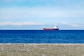 Cargo ship in open sea against the background of snow covered mountains. Royalty Free Stock Photo