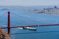 Cargo ship passing under Golden Gate Bridge on a sunny day; San Francisco skyline in the background; California