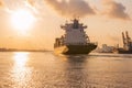 Cargo ship is sailing out of the harbor at evening to sea to transport cargo in the container.