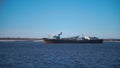 Cargo ship sailing on river on clear day. Clip. Merchant ship or barge sails along river. Commercial and industrial