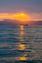 Cargo ship sailing the sea at a golden sunset or sunrise. Ocean shipment across water as the sun sets or rises. Harmony and beauty Royalty Free Stock Photo