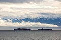 Cargo ship and tanker in transit in front of the Olympic Mountain range, Washington, USA