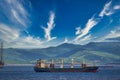 Cargo ship in the water with a background of green mountains under the cloudy sky Royalty Free Stock Photo