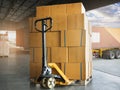 Cargo shipment boxes. Freight truck. Delivery service. Stack of package boxes on pallet with hand pallet truck. Royalty Free Stock Photo