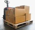 Cargo shipment boxes, Manufacturing and warehousing. Stack of cardboard boxes on pallet and Electric forklift pallet jack. Royalty Free Stock Photo