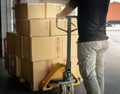 Cargo shipment boxes, Warehousing. Worker working with hand pallet truck unloading cargo boxes on pallet at the warehouse. Royalty Free Stock Photo