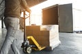 Warehouse worker working with hand pallet truck loading package boxes on pallet into cargo container.