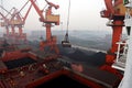 Cargo terminal for discharging coal cargos by shore cranes during foggy weather. Port Bayuquan,China. Royalty Free Stock Photo