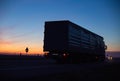 A cargo truck drives on the motorway in the evening against the backdrop of sunset. Truck logistics and transportation concept,