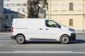 Cargo van Peugeot Expert driving in the city street. White minivan in motion, side view