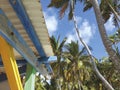 Caribbean house structure with colored wooden beams and sheet metal roof. Tropical blue sky and palm trees. Paradise landscape. Royalty Free Stock Photo