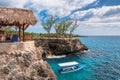 Caribbean rocky beach with turquoise water, tourists boat and lighthouse in Negril Jamaica.