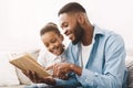 Caring african-american daddy reading book to his cute daughter Royalty Free Stock Photo