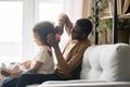 Caring African American father brushing combing preschool daughter hair