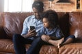 Caring African American father with little daughter using smartphone together