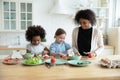 Caring african american mommy teaching little girls cooking.